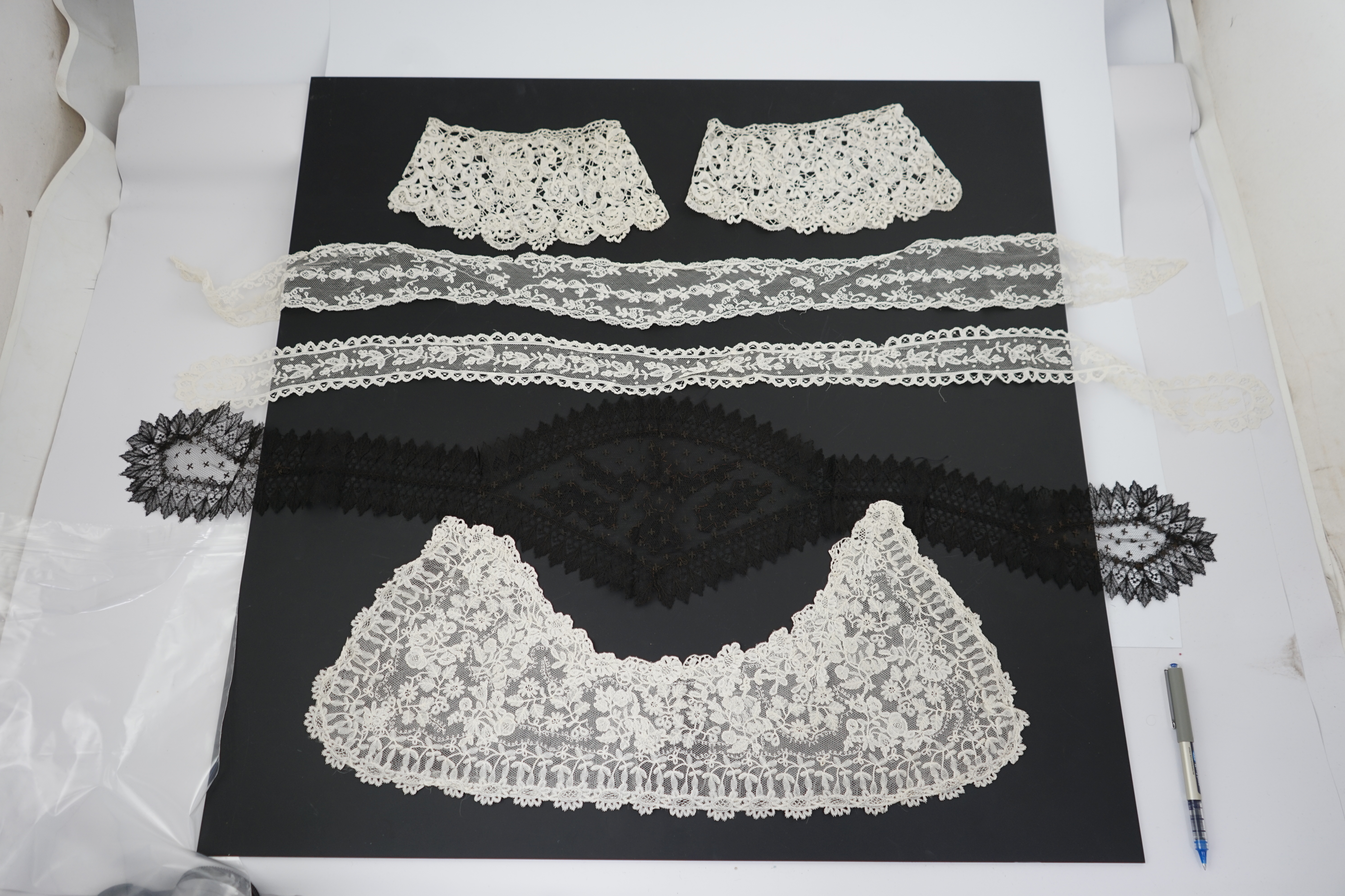 A small collection of late 19th century laces including a cream Brussels bobbin lace collar appliquéd on to net and two similar Brussels bobbin lace lappets, a pair of cream Honiton bobbin lace cuffs and a black lace fal